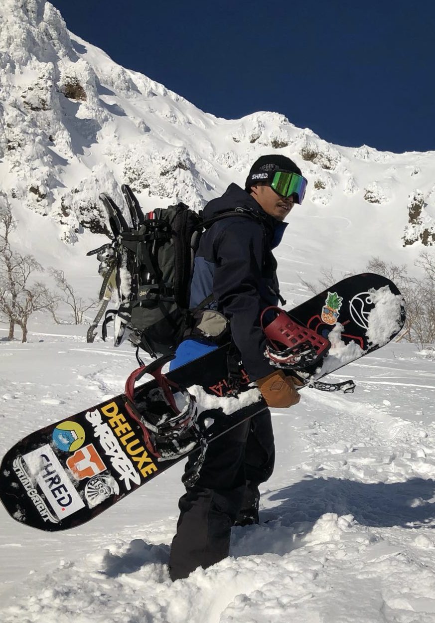 平山武背著雪板站在雪山前的既有選手照片
